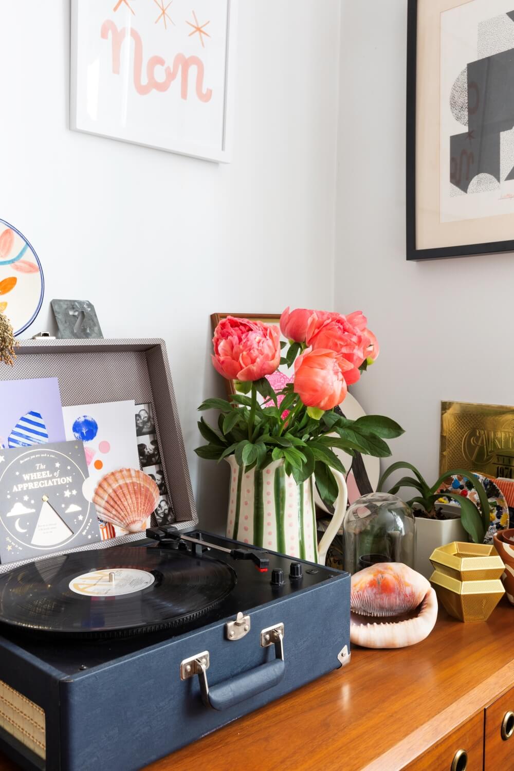 record player on west elm dresser next to vase of peonies 