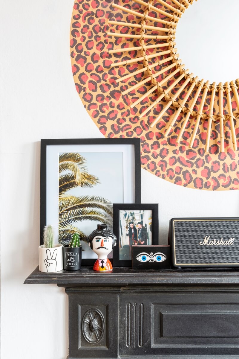 A colourful rental: leopard print behind mirror above black fireplace
