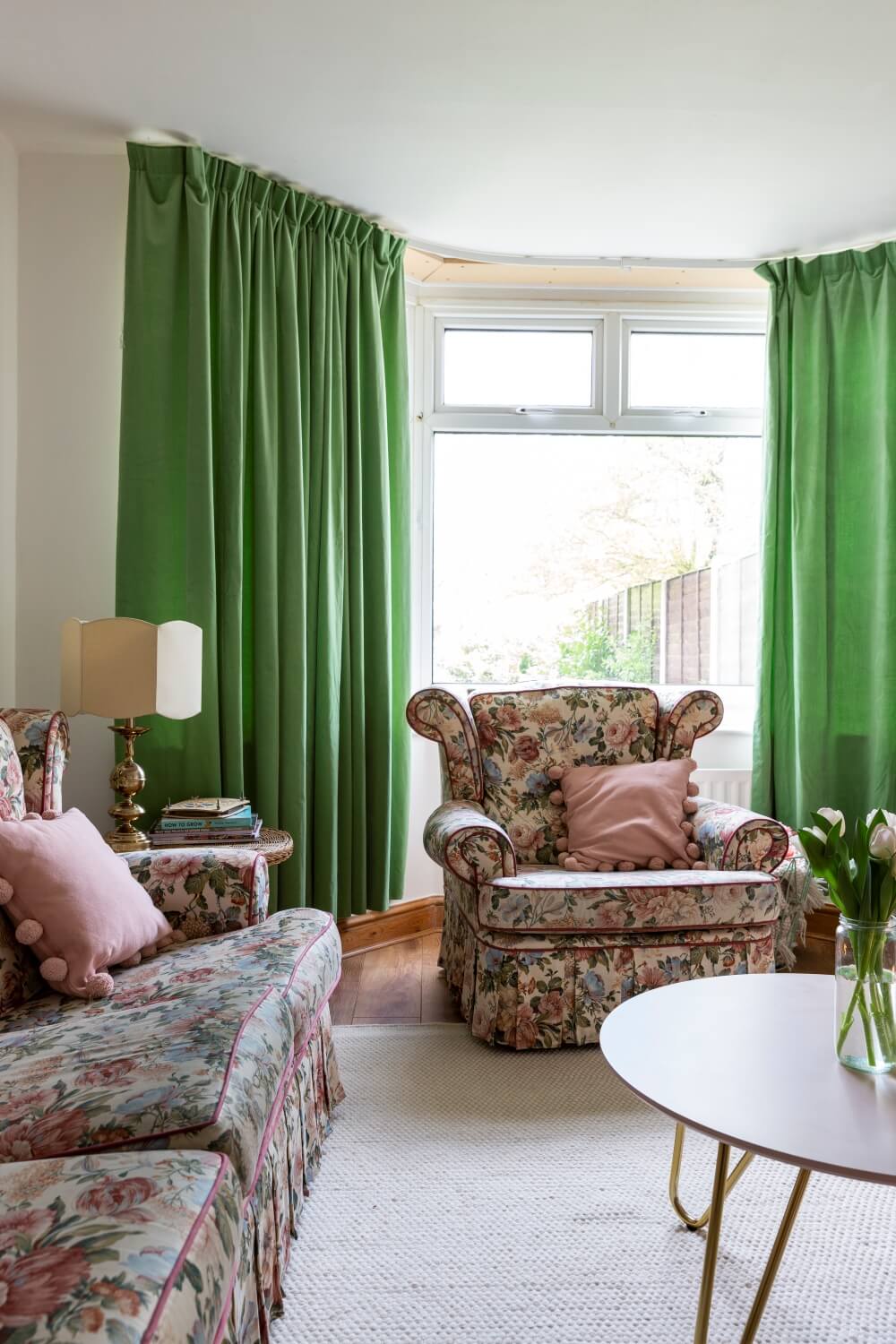 Decorate with Pink Home tour: floral vintage sofa arm chair in front of large bay window framed with lined green curtains. 