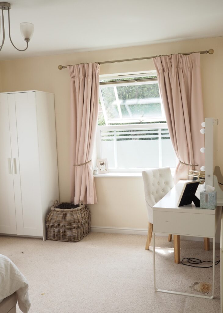 Dressing table in front of the window with pink curtains 