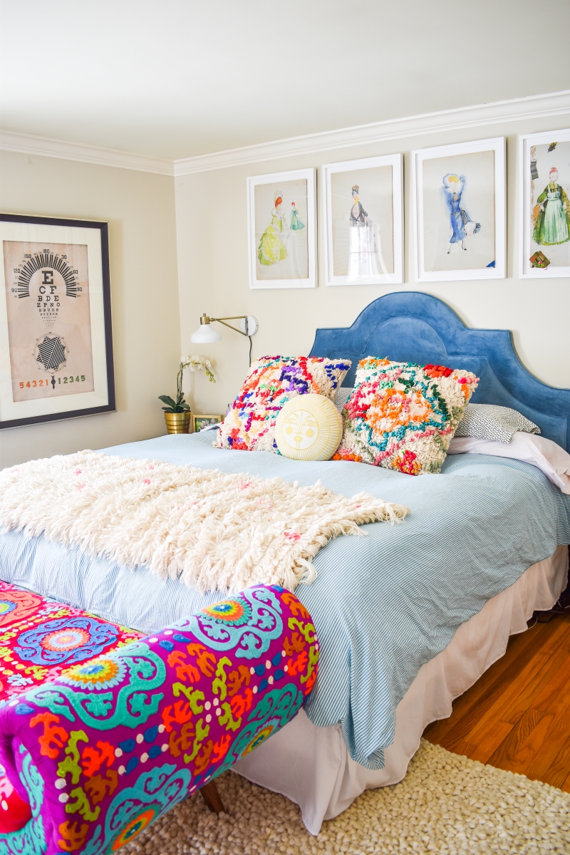 Colourful master bedroom with blue headboard and watercolour with gallery wall