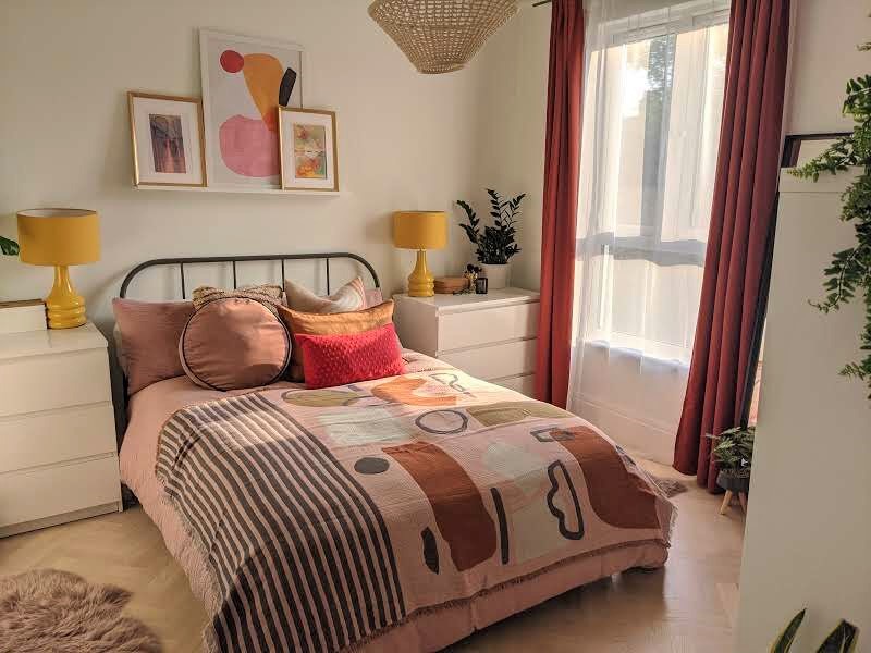 colorful URBAN MODERN BEDROOM WITH ABSTRACT BED THROW. YELLOW LAMPS AND PINK CURTAINS