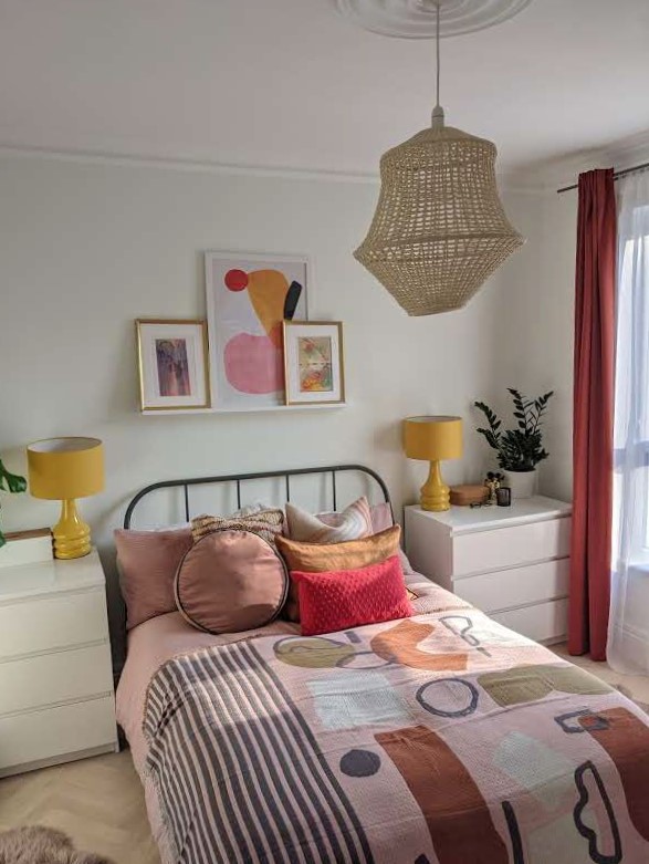 colorful URBAN MODERN BEDROOM WITH ABSTRACT BED THROW on bed with assorted pillows. YELLOW LAMPS AND PINK CURTAINS