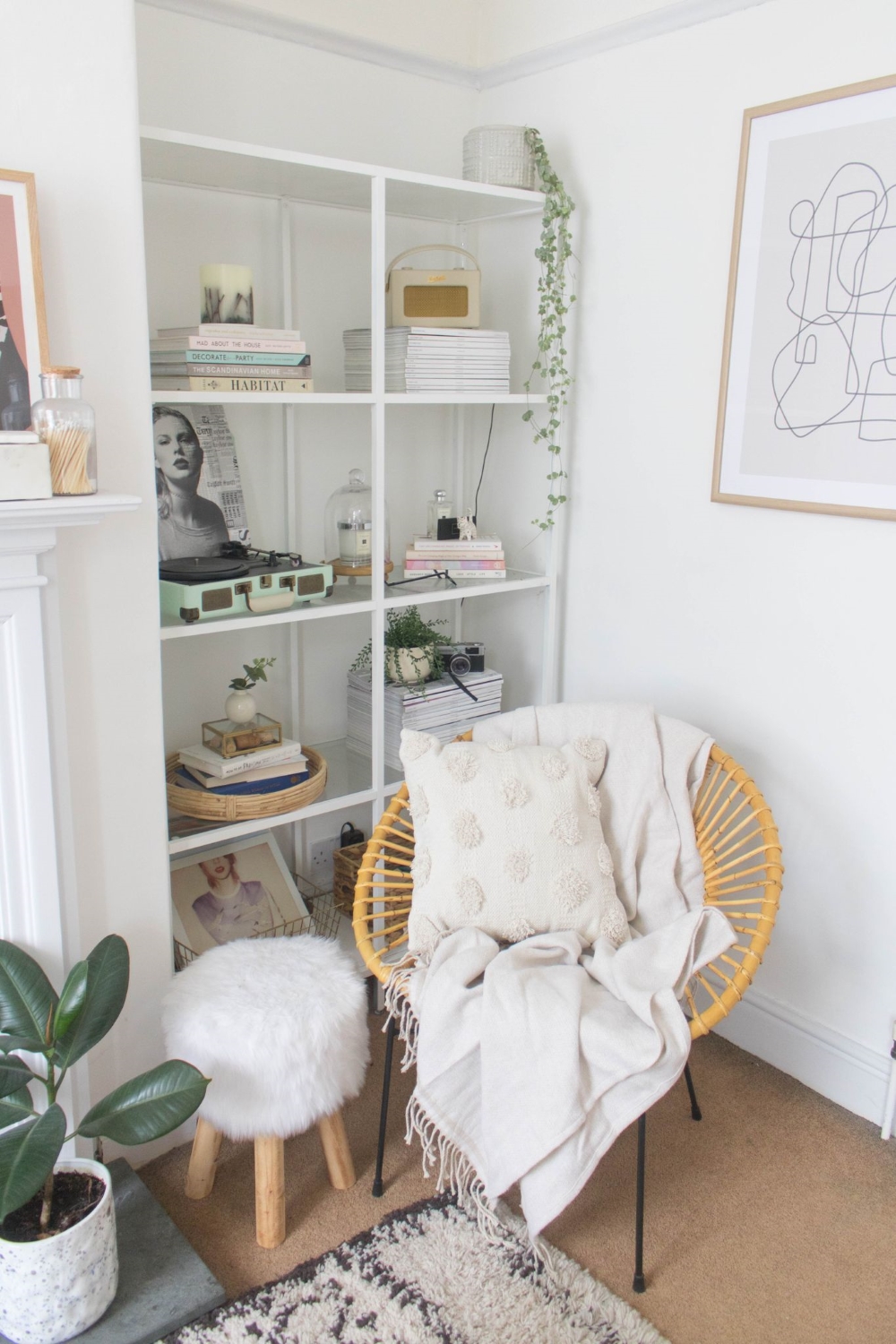White shelving with a rattan corner seat draped with a throw 